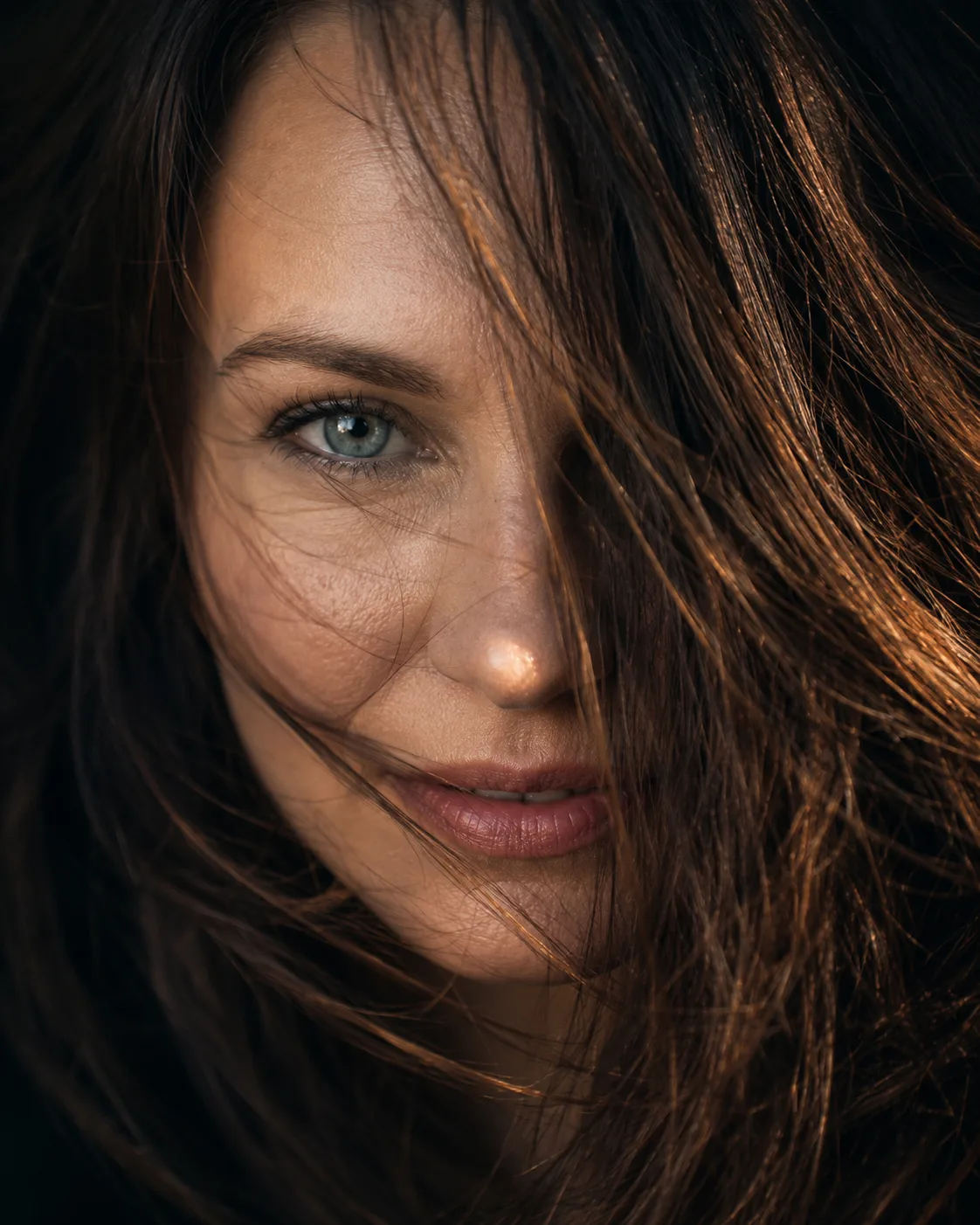 A  close-up portrait of a woman with hair blowing across her face